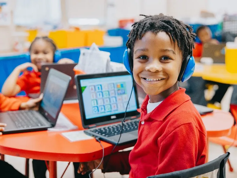 Smiling boy, blue headphones, computer